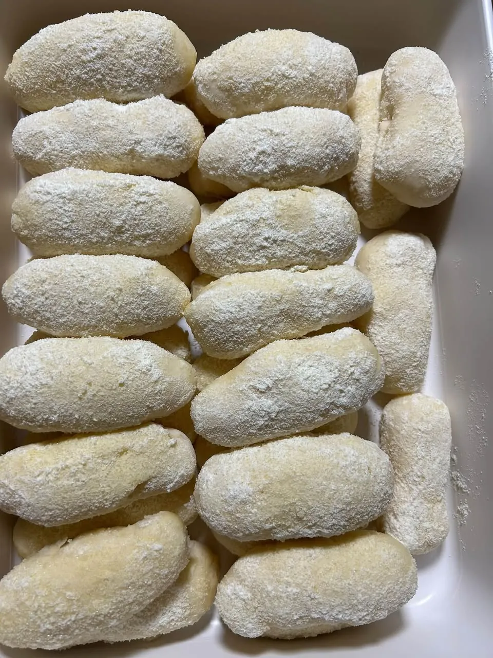 A tray of soft homemade cheese rolls dusted with sugar