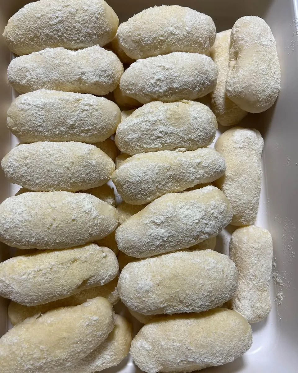 A tray of soft homemade cheese rolls dusted with sugar