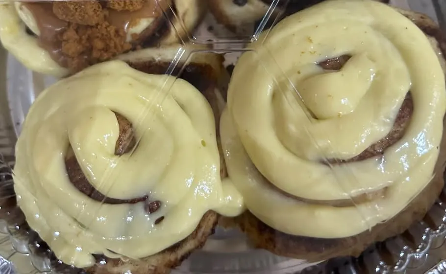 Two cinnamon rolls with thick frosting swirls, seen from above