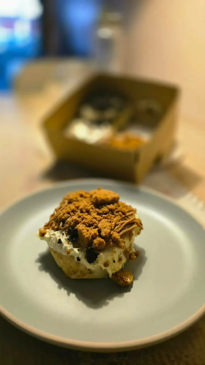 A cinnamon roll with biscuit crumble on a plate